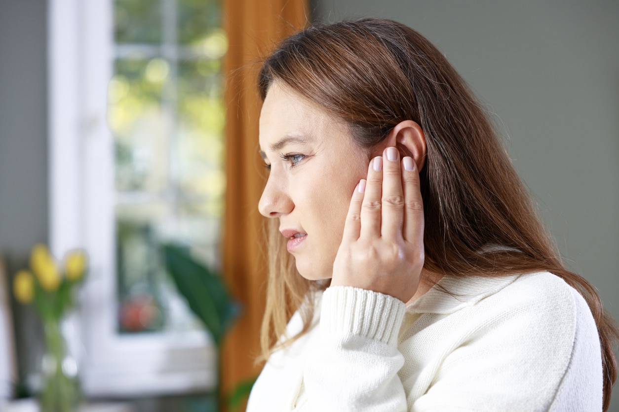 Young woman with tinnitus holding her left ear