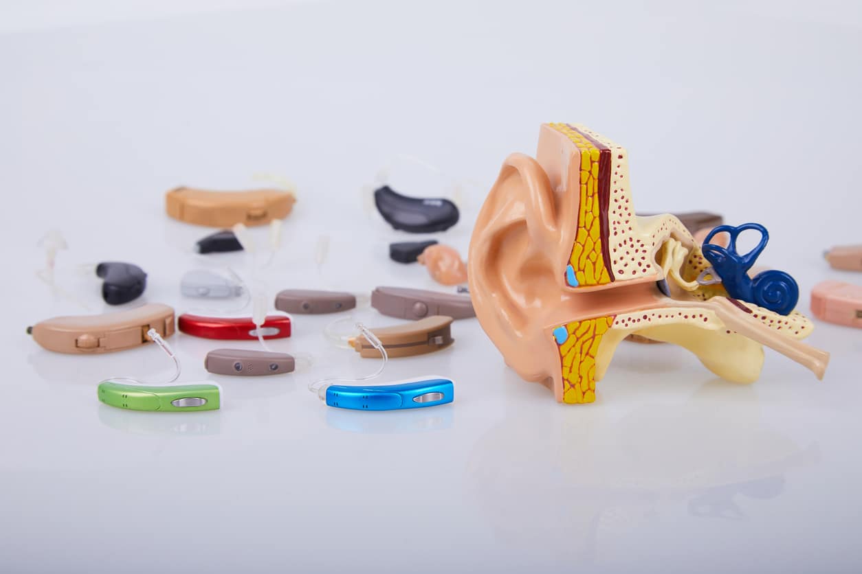 Hearing aid collection next to an ear model.
