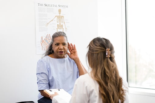 Woman talking to her doctor, holding her hand to her ear.