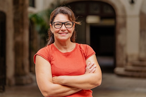 Smiling positive lady portrait arms crossed in a town street.