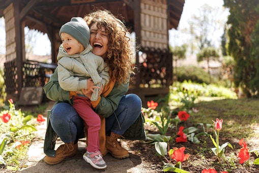 Mother and cute little daughter admiring blooming nature on early spring day.