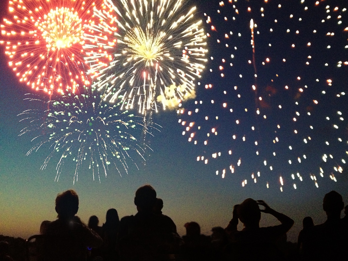 Fourth of July Fireworks Exploding Over Celebrating Spectators in Silhouette